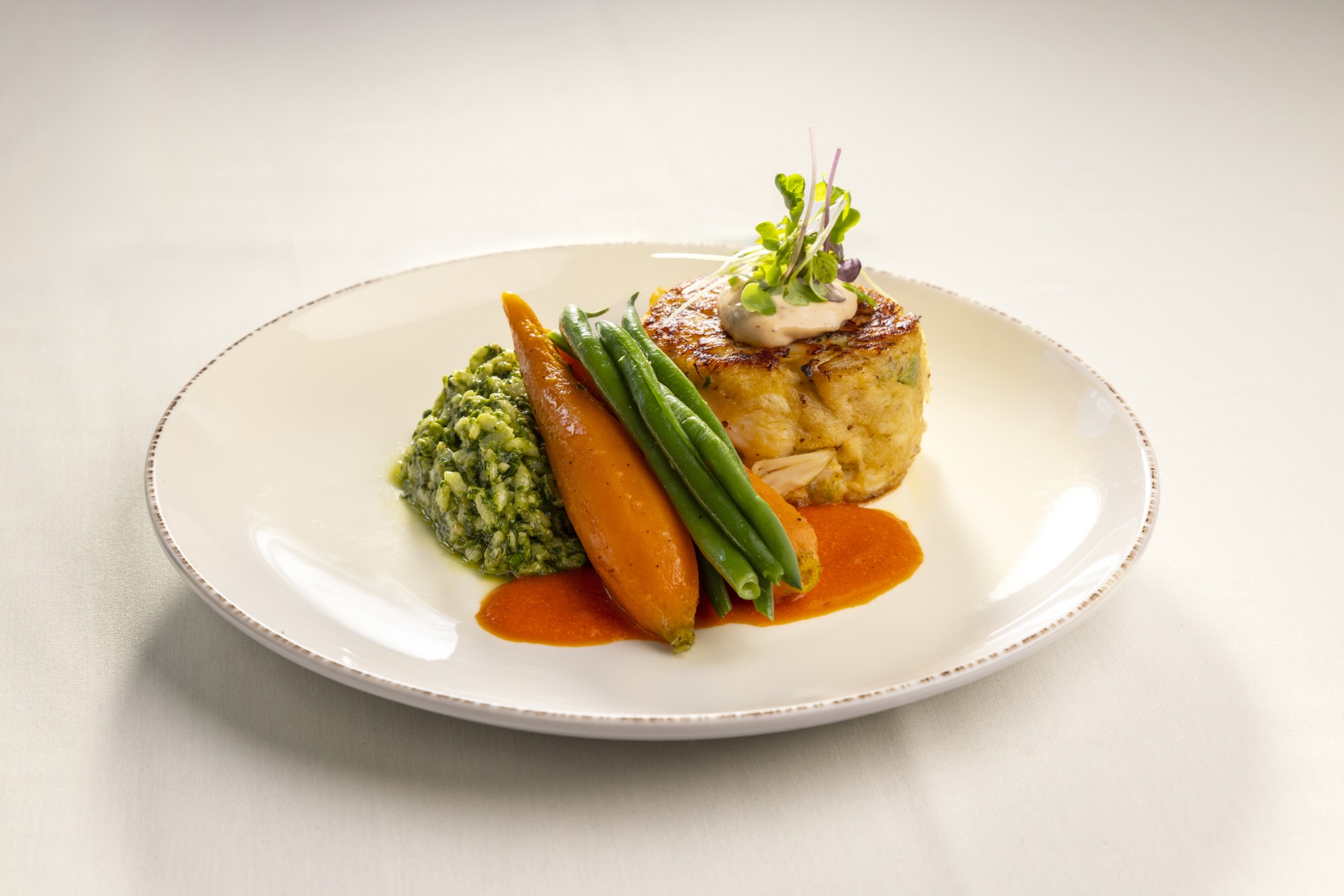A chef-prepared crab cake entrée with glazed carrots and green beans
