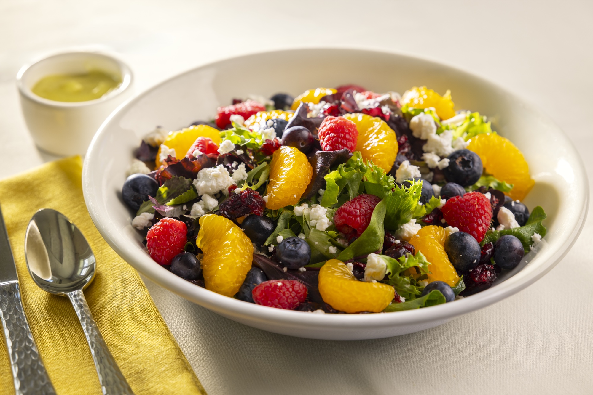A mixed greens salad with berries, mandarin oranges and goat cheese